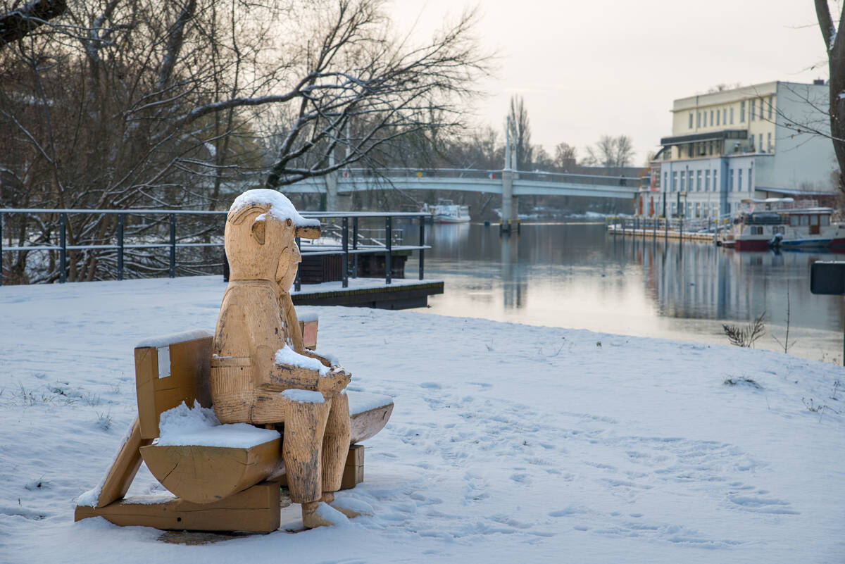 Loriot-Figur aus Holz in Lebensgröße auf einer Bank im Schnee