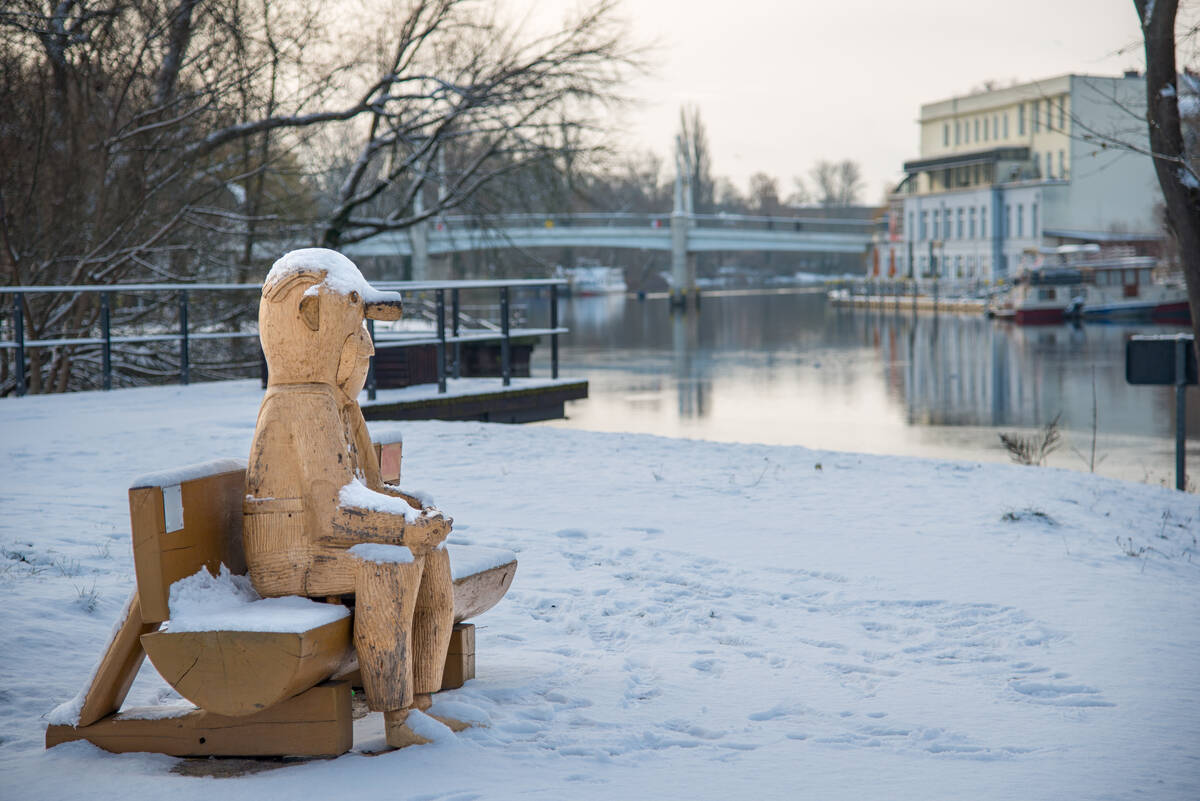 Loriot-Figur aus Holz in Lebensgröße auf einer Bank im Schnee